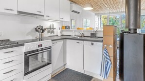 A modern kitchen with white cabinets, a stainless steel oven, a dishwasher, and a wooden ceiling. - "Catha" - 200m from the sea by Interhome (Væggerløse)