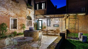 A courtyard with a brick wall, outdoor seating, and a small garden area. - The Secret Garden of Venice Sanctuary: A Peaceful Getaway (Venezia)