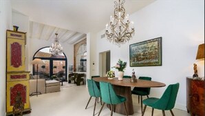 A dining area with a round wooden table, green upholstered chairs, and a chandelier. - The Secret Garden of Venice Sanctuary: A Peaceful Getaway (Venezia)