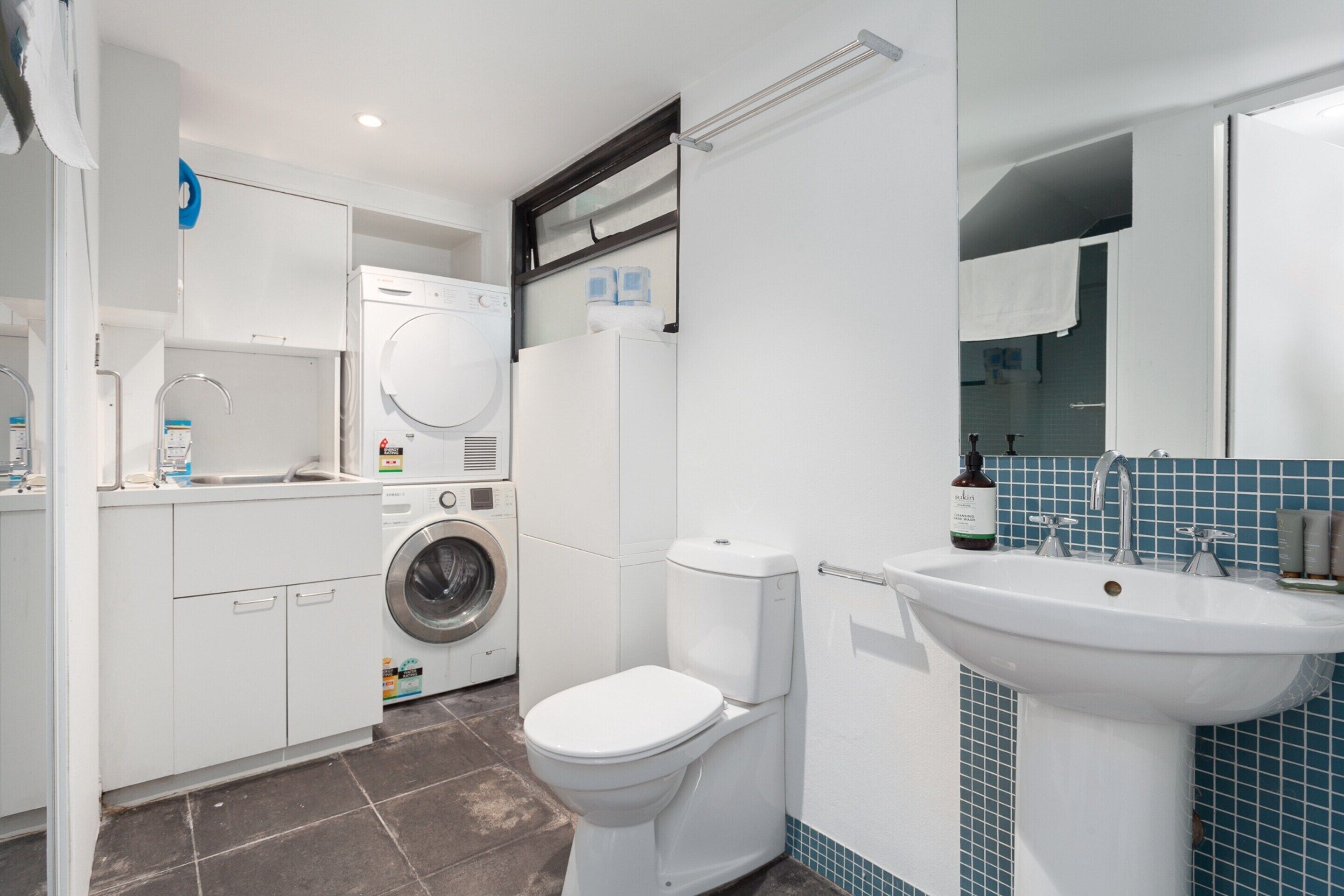 A modern bathroom with a toilet, sink, and washing machine.