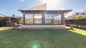 A modern house with large glass windows, a patio, and a well-maintained lawn. - Frank's House, a villa surrounded by greenery with a private pool (Piana Calzata)