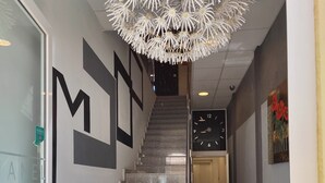 A staircase with a modern design, leading to a room with a clock and a door. - Hostal Manel (Pineda de Mar)
