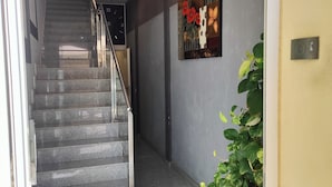 A staircase leading to a landing with a decorative ceiling light, a wall-mounted sign, and a potted plant. - Hostal Manel (Pineda de Mar)