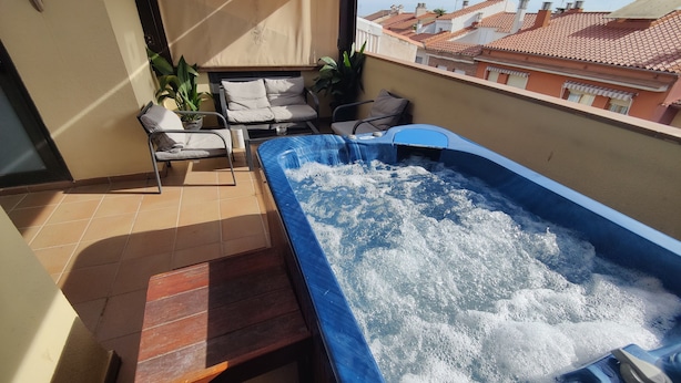 A rooftop terrace with a hot tub, a wooden table, and two chairs. - Hostal Manel (Pineda de Mar)