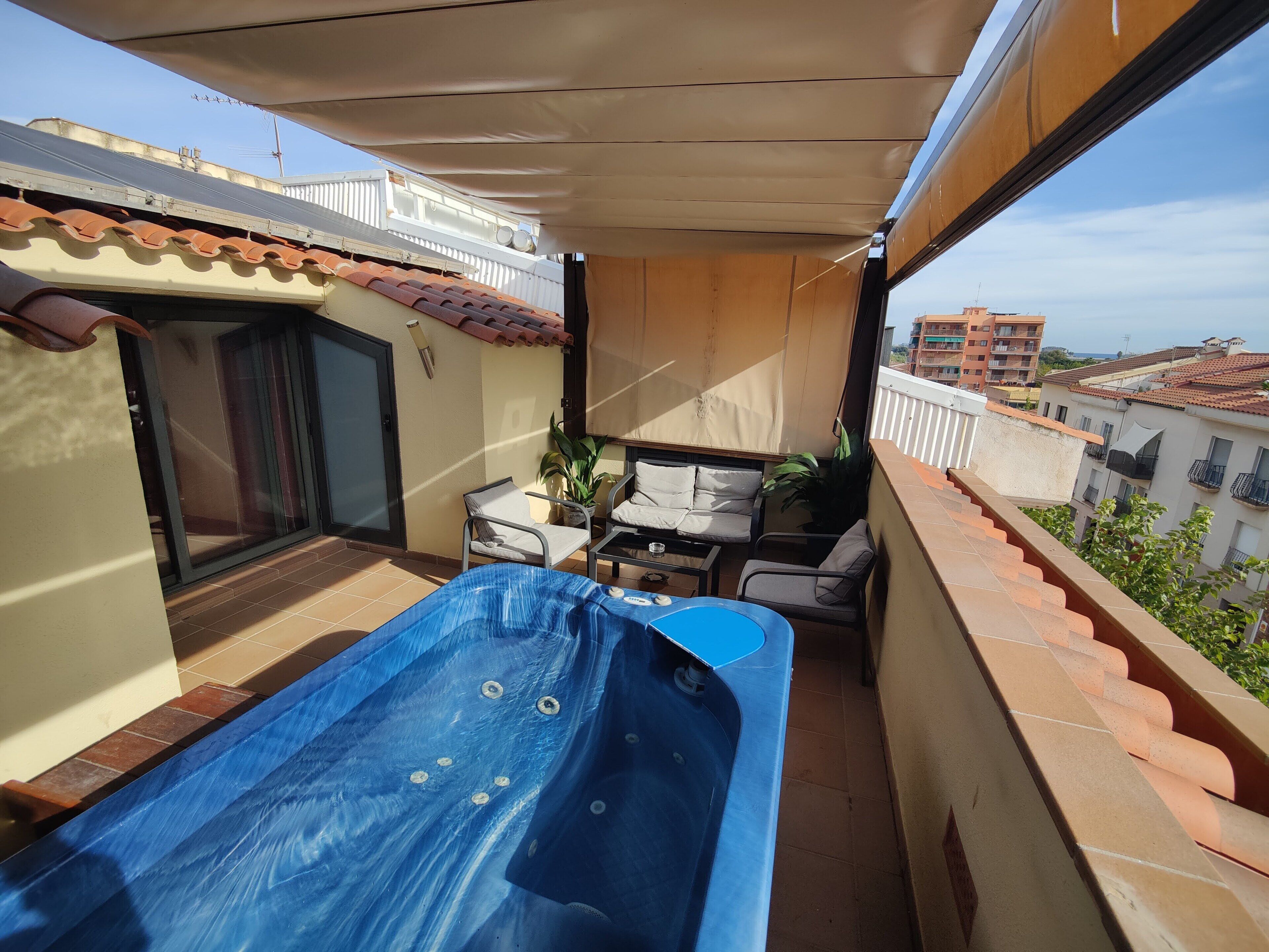 Un balcon avec un jacuzzi bleu, une table et deux chaises.