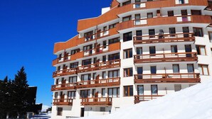 A multi-story hotel with balconies, white exterior, and a snowy environment. - Classic Studio Ski-in/ski-out (Les Belleville)