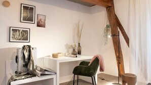 A modern living room with a white desk, a green chair, and a wooden ceiling beam. - Hotelfuchs (Saarbrücken)