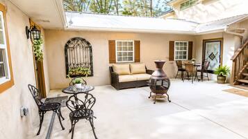 A covered patio area with a sofa, chairs, a table, and a decorative urn.