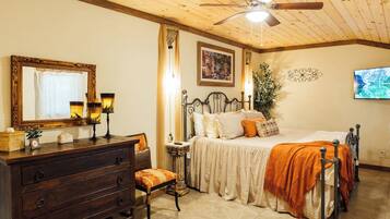 A bedroom with a bed, dresser, mirror, ceiling fan, and a painting on the wall.