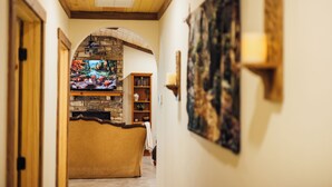 Ein gemütlicher Innenraum mit Kamin aus Stein, Holzbalkendecke und Bücherregal.