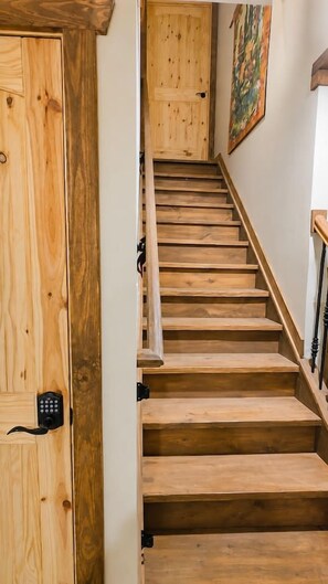 A wooden staircase with a handrail, leading to a door with a keypad lock. - Villa Serena Tuscan theme home-hidden fantasy room (Dahlonega)