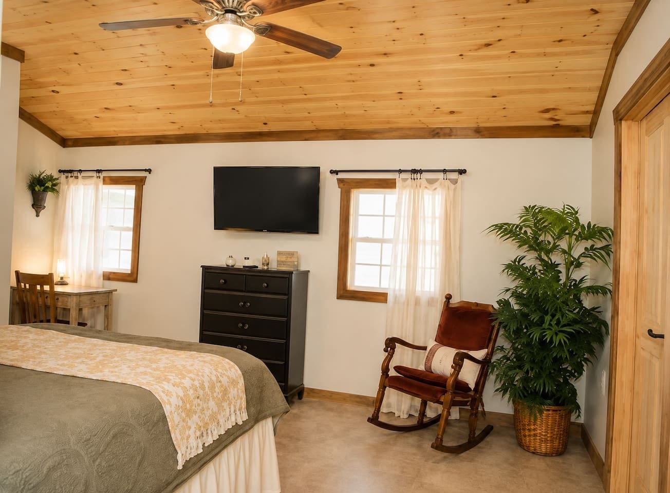 Un dormitorio con cama, cómoda, televisor, sillón mecedora y planta en maceta.