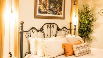 A bed with a black metal headboard, white bedding, and a framed painting above.