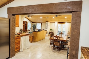 A kitchen with a wooden island, a dining area with a table and chairs, and a view through an archway. - Villa Serena Tuscan theme home-hidden fantasy room (Dahlonega)