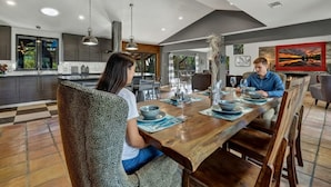 Une cuisine moderne avec des meubles de couleur sombre, un grand îlot central et des luminaires suspendus.