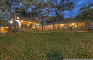 A residential property with a large open patio, a covered outdoor dining area, and a well-maintained lawn. - Terracotta Oasis - Wimberley for 30 Guests (Wimberley)