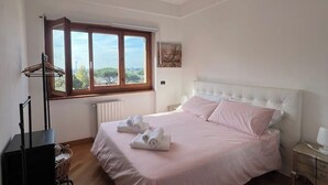 Een slaapkamer met een groot bed, een raam met uitzicht, een radiator en een nachtkastje.