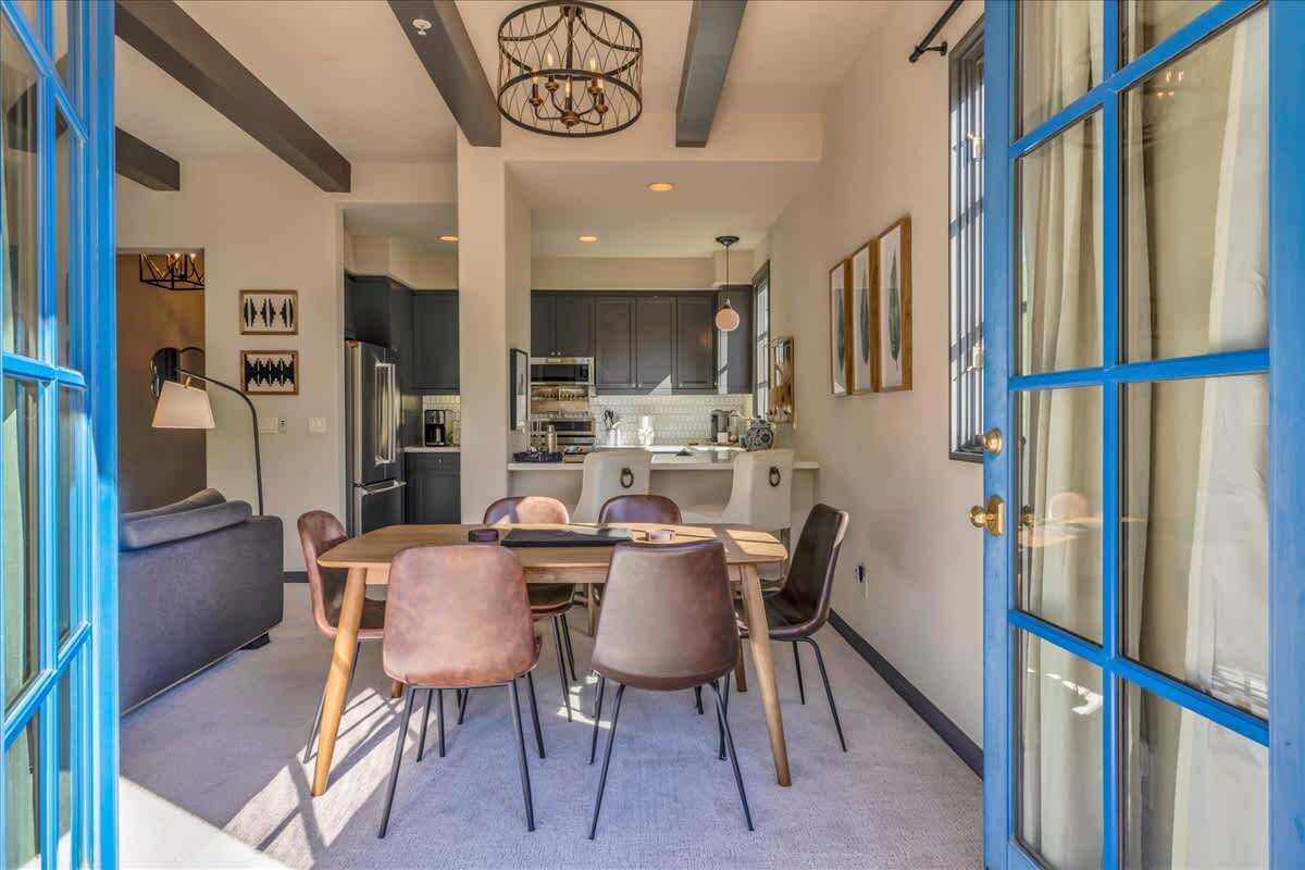 A modern kitchen with dark cabinets, a central island, and a dining area with a table and chairs.