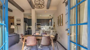 Una cocina moderna con armarios oscuros, una isla central y una zona de comedor con mesa y sillas.