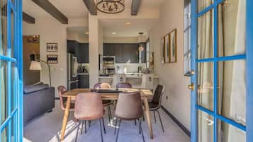 A modern kitchen with dark cabinets, a central island, and a dining area with a table and chairs.
