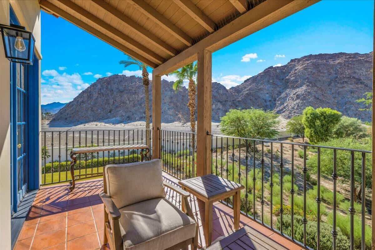 Un balcón con una silla y una mesa, con vistas a un paisaje montañoso.