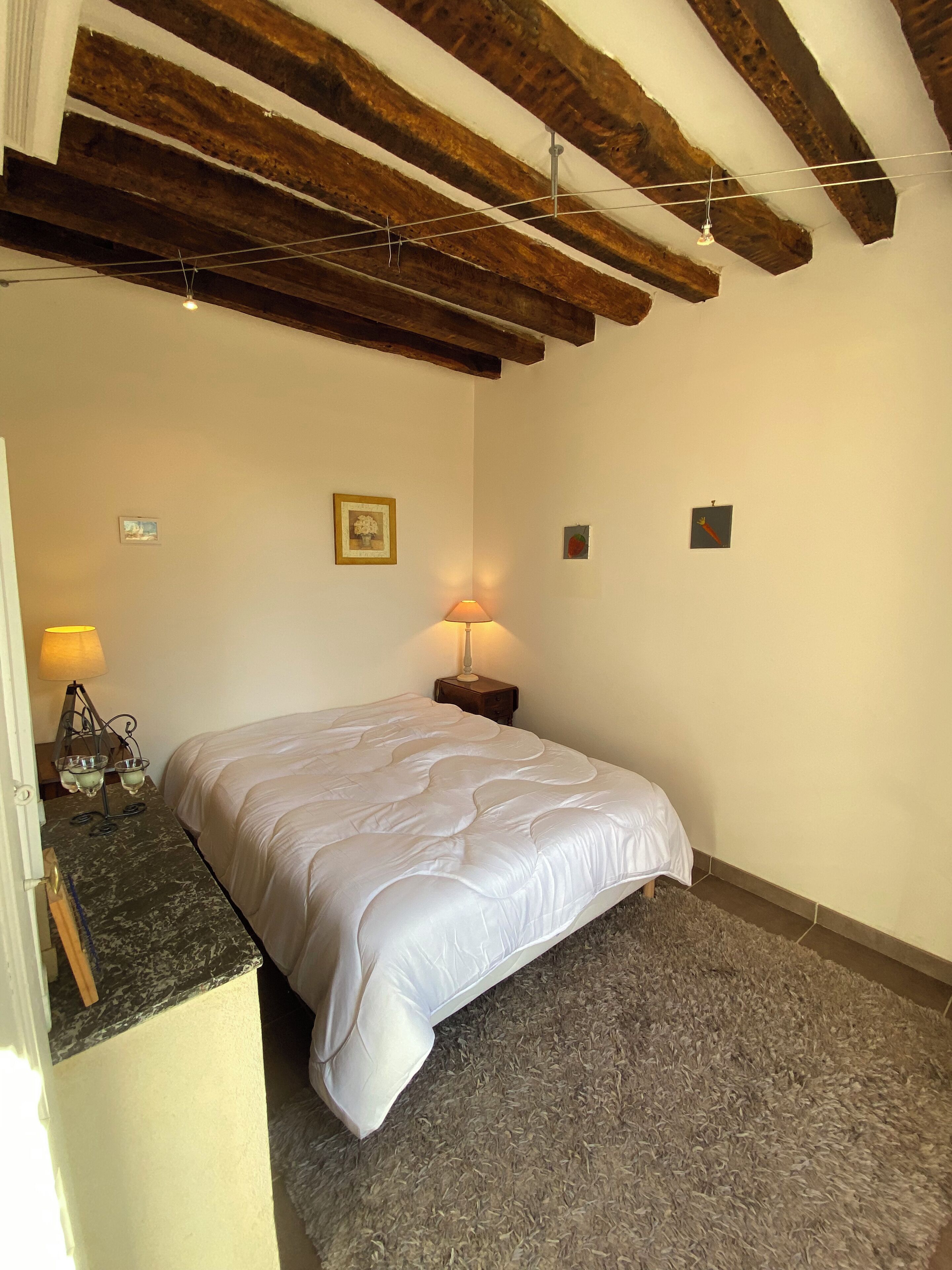 A bedroom with a bed, a nightstand, a lamp, and a picture on the wall.
