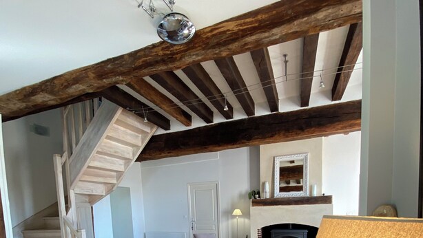 Un amplio salón con una escalera, una chimenea y un sofá moderno.