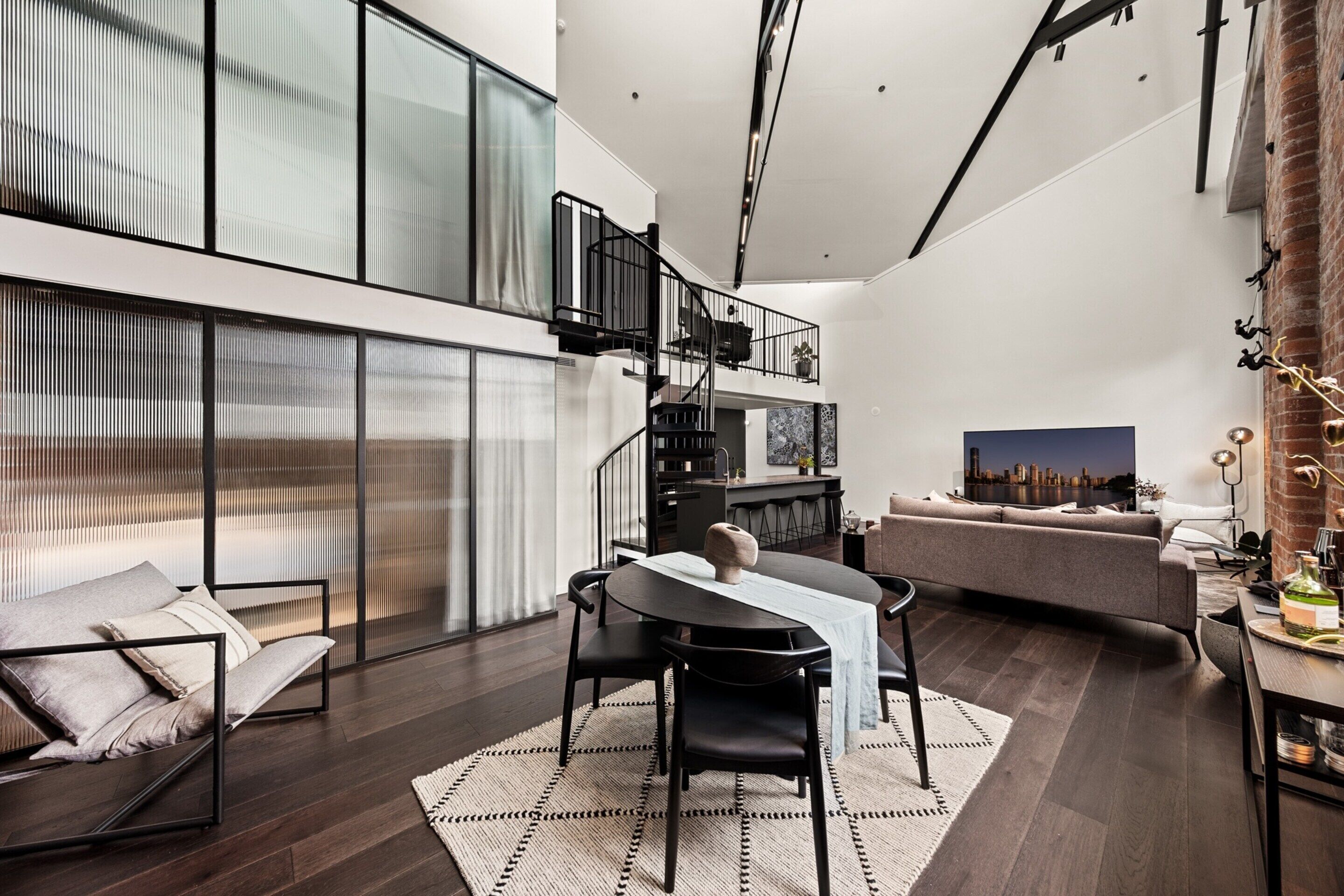 Un espacio habitable moderno con comedor, sofá y una escalera que sube a un nivel superior.