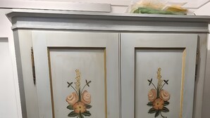 Un meuble à deux portes orné de motifs floraux et doté d’une porte en treillis métallique.