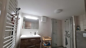 Une salle de bain moderne avec un lavabo blanc, un meuble-lavabo en bois et une cabine de douche en verre.