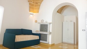A room with a blue sofa, a fireplace, and a wardrobe. - Dimora San Felice - Il Mandorlo (Gallipoli)