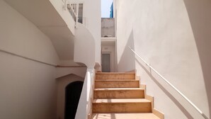 A narrow stairway with white walls and a wooden handrail, leading to a door at the top. - Dimora San Felice - Il Mandorlo (Gallipoli)