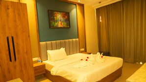 A hotel room with a large bed, a painting on the wall, a wooden wardrobe, and a window with curtains. - Skyye Nature Resort (Malakhera)