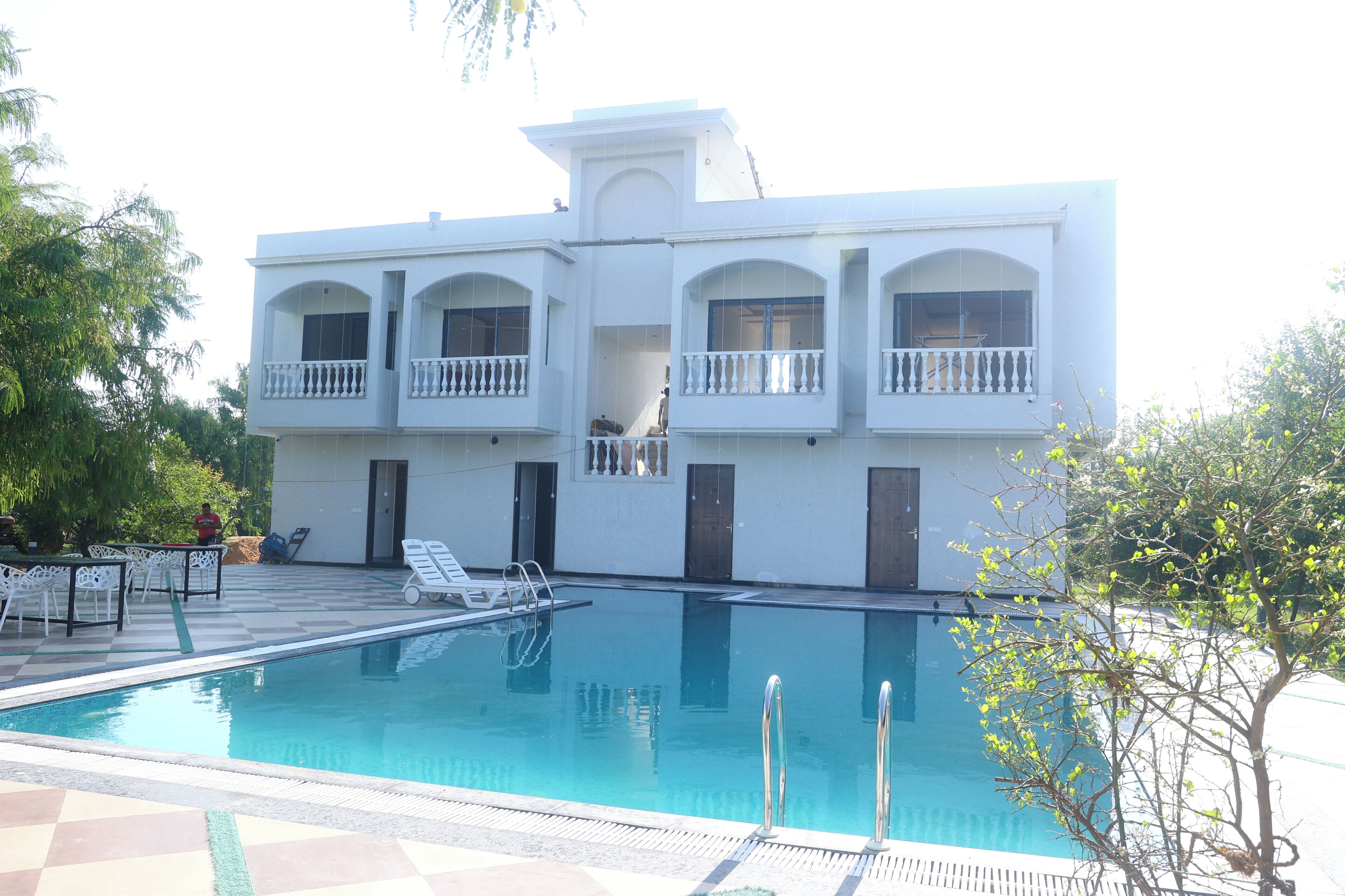 Un edificio blanco con piscina, mobiliario exterior y un balcón.
