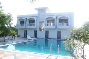 A white building with a swimming pool, outdoor seating, and a balcony. - Skyye Nature Resort (Malakhera)