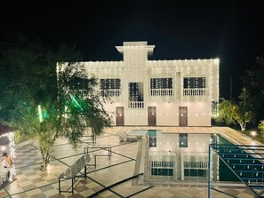 A modern building with a pool, surrounded by a checkered floor and trees. - Skyye Nature Resort (Malakhera)