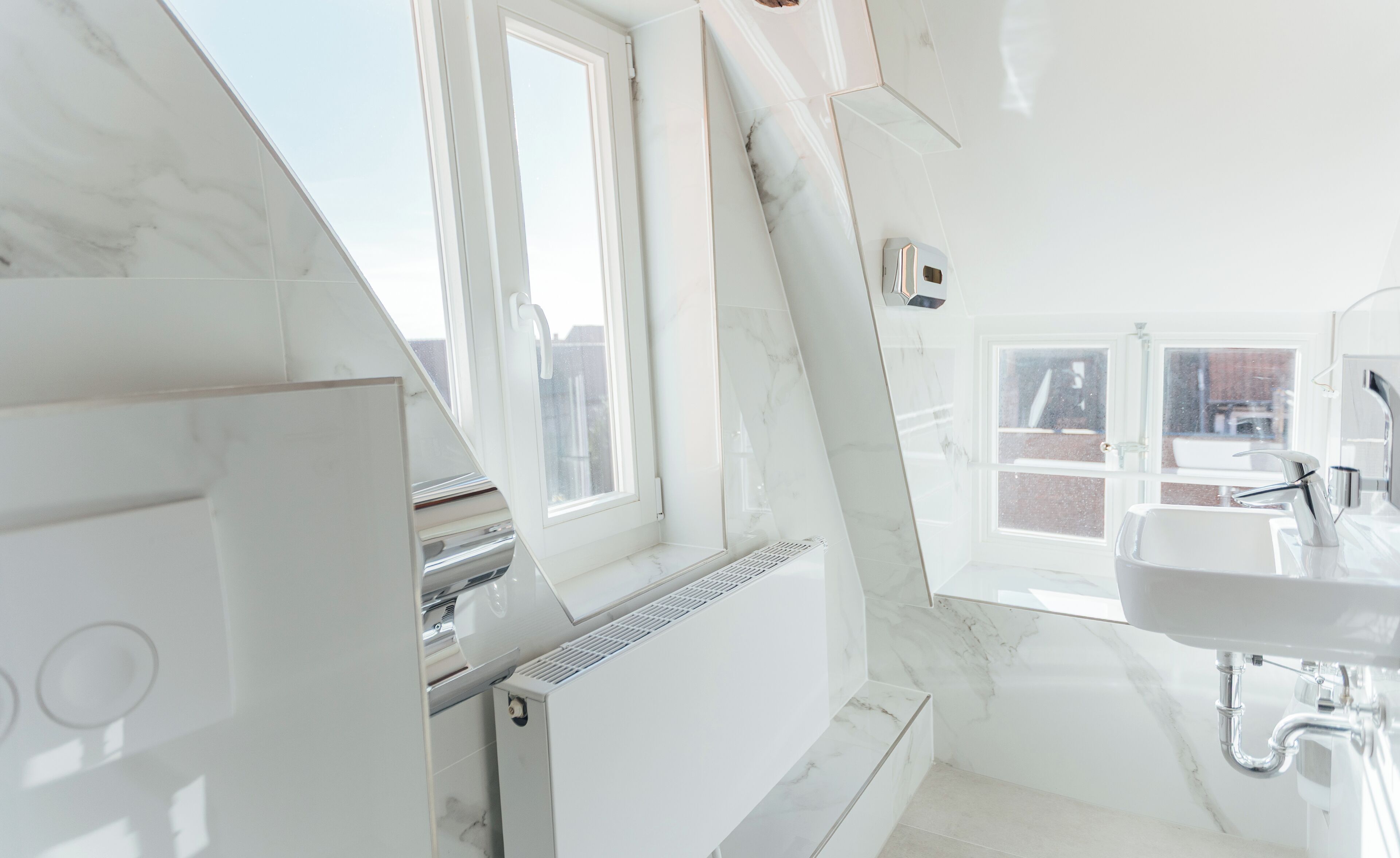 A modern bathroom with a skylight, a built-in sink, and a radiator.