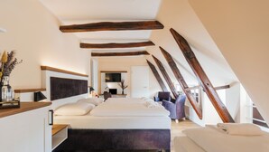 Une chambre moderne avec un grand lit, des poutres en bois et une vue sur la pièce adjacente.
