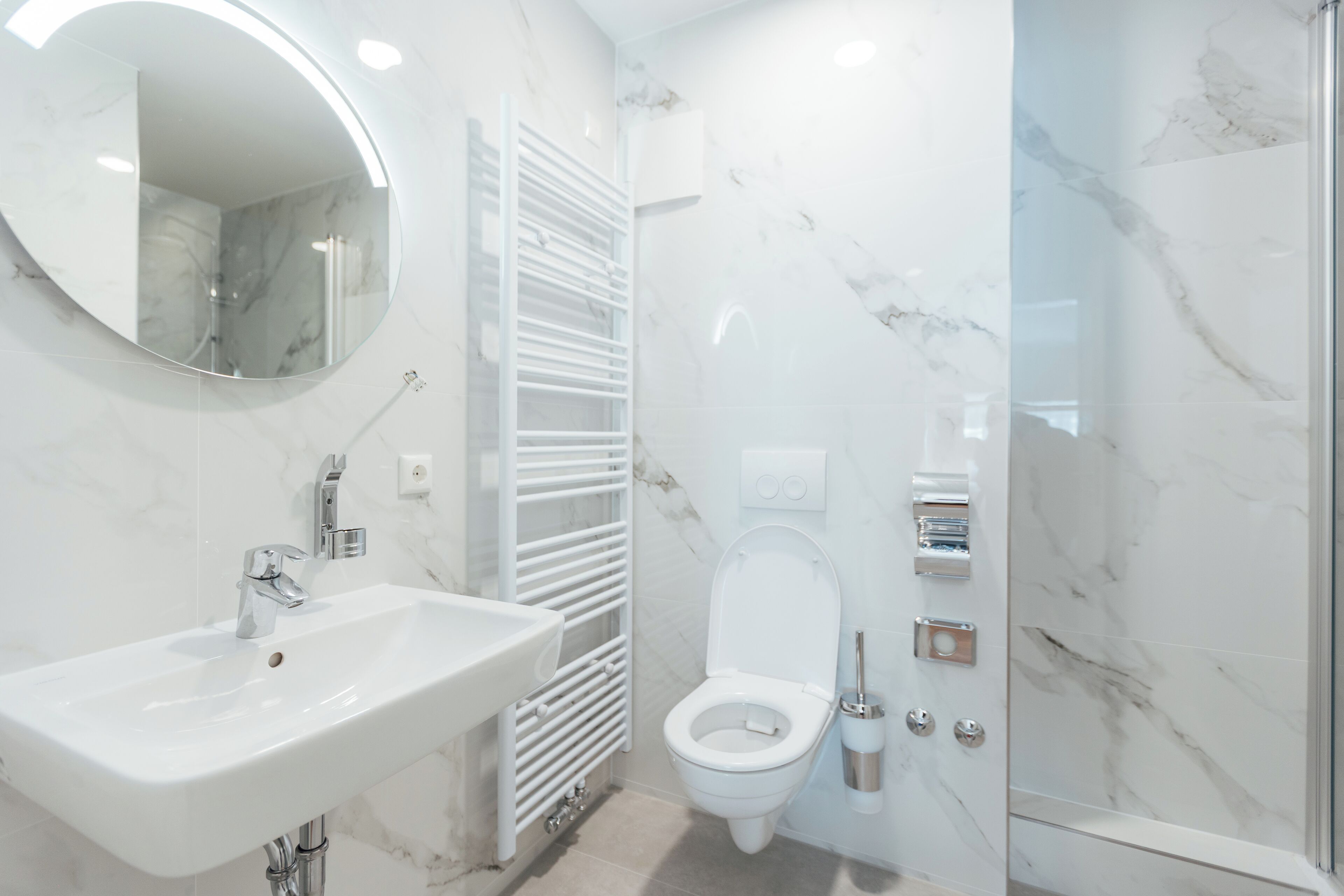 A modern bathroom with a white sink, a toilet, and a glass shower enclosure.