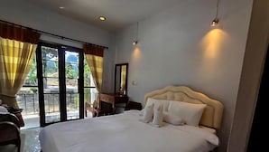 A hotel room with a large bed, a desk, a chair, and a view through a glass door. - A-Thip House (Pai)