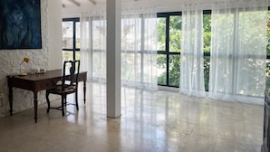 A spacious room with a large window, a desk with a chair, and a painting on the wall. - Bright, quiet loft within walking distance - Exceptional location (Le Gosier)