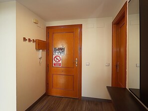 A wooden door with a no-smoking sign, a phone, and a light switch on the wall. - Diamonds Sea View – Apartamento frente al mar con terraza y capacidad para 6 personas (Lloret de Mar)