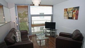 Una sala de estar con un sofá, una mesa de centro, un televisor y un cuadro en la pared.