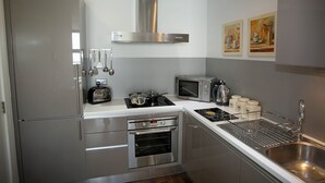 Una cocina moderna con electrodomésticos de acero inoxidable, microondas, hervidor y pileta.
