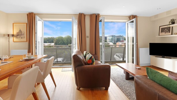 A modern living room with a dining area, large windows, and a flat-screen TV. - River View in Newcastle Upon Tyne (Newcastle-upon-Tyne)