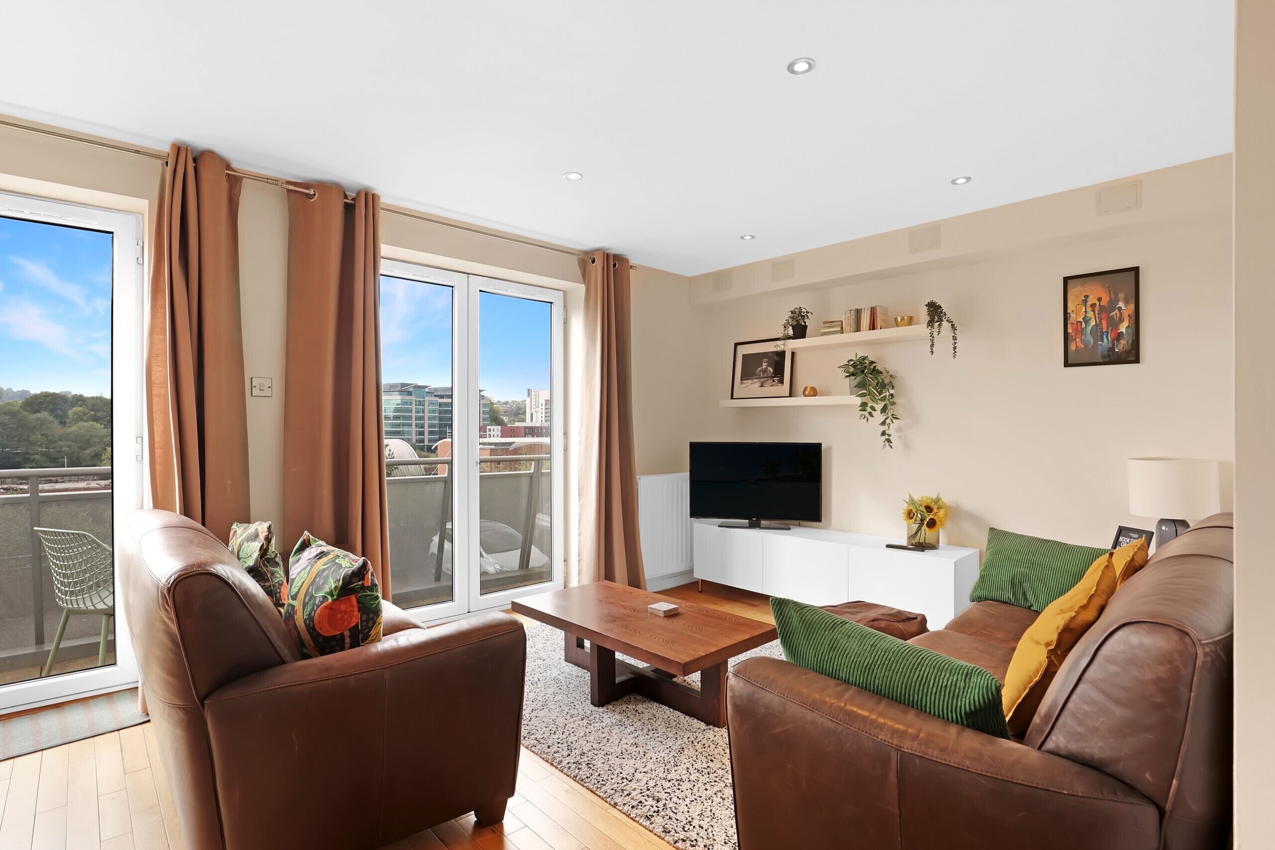 A modern living room with leather sofas, a wooden coffee table, and a flat-screen TV.