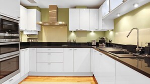 A modern kitchen with white cabinets, stainless steel appliances, and a black countertop. - River View in Newcastle Upon Tyne (Newcastle-upon-Tyne)