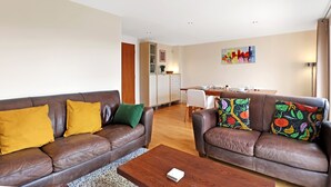 A modern living room with two brown leather sofas, a wooden coffee table, and a dining area in the background. - River View in Newcastle Upon Tyne (Newcastle-upon-Tyne)