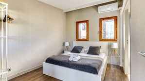 Een slaapkamer met een bed, twee nachtkastjes, een kledingkast en een airconditioning.