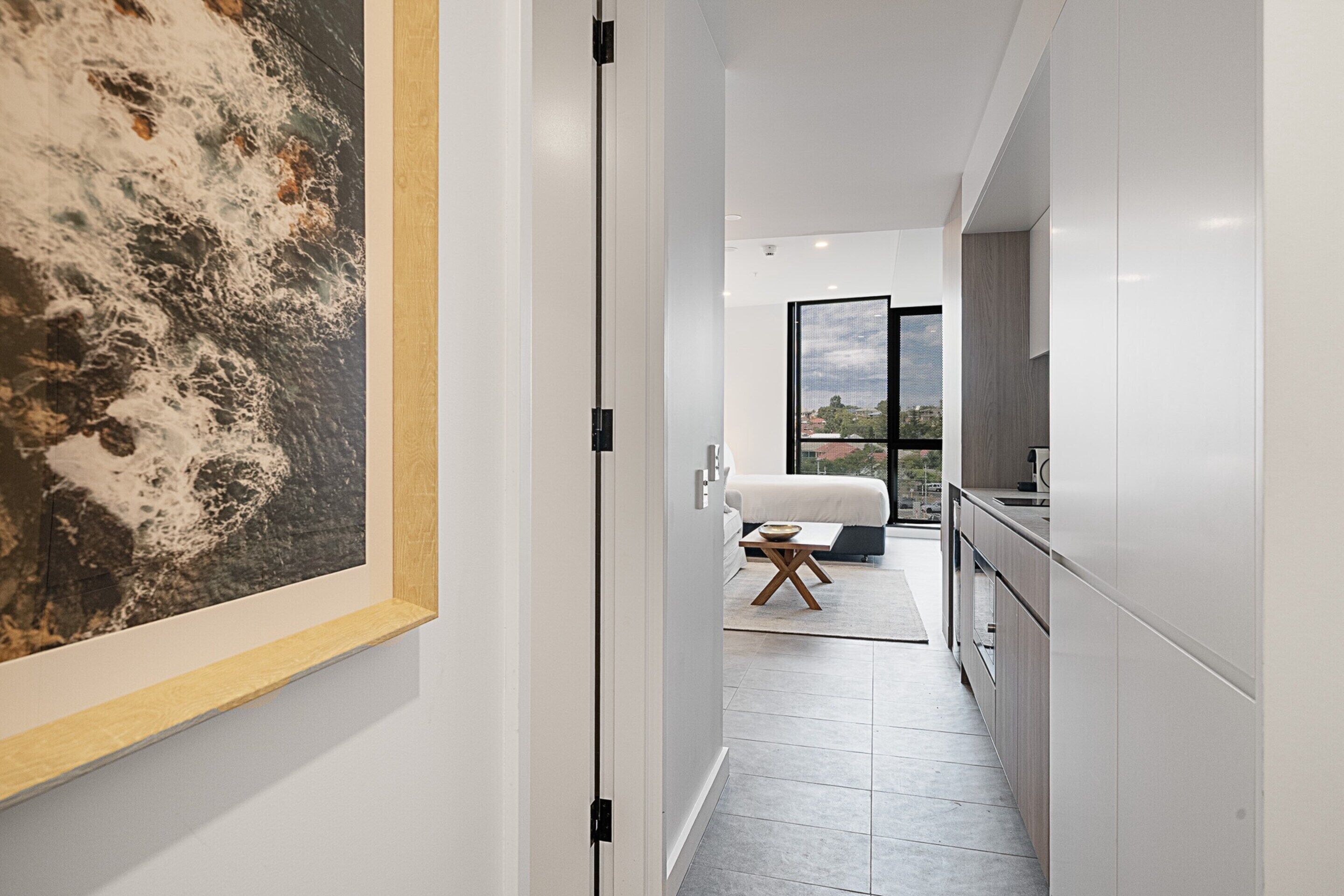 A modern kitchen with white cabinets and a large window.